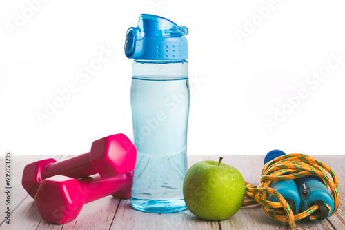 Healthy lifestyle . Fitness equipment ,Water of bottle, green apple , jump rope on wooden table on white photo