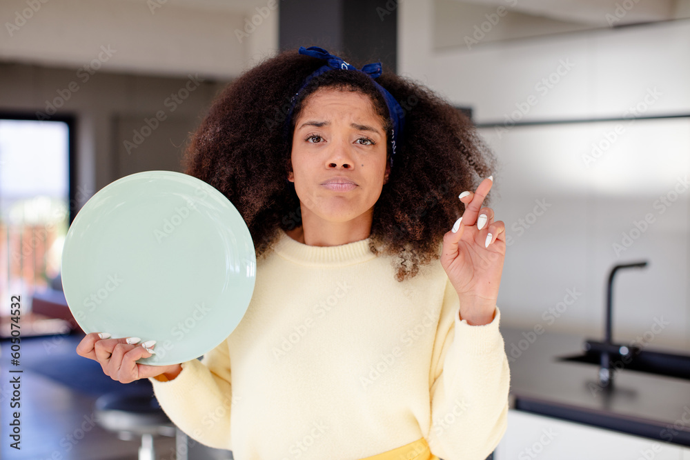 pretty afro black woman crossing fingers and hoping for good luck. home chef concept