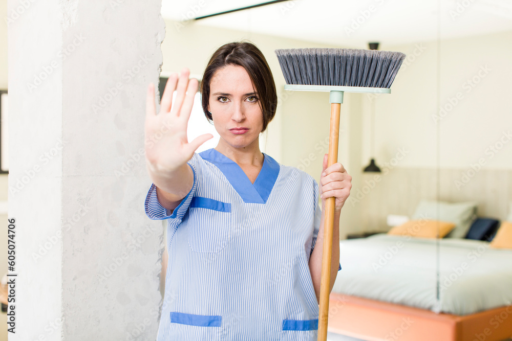 young pretty woman looking serious showing open palm making stop gesture. housekeeper concept young pretty woman looking serious showing open palm making stop gesture. housekeeper concept