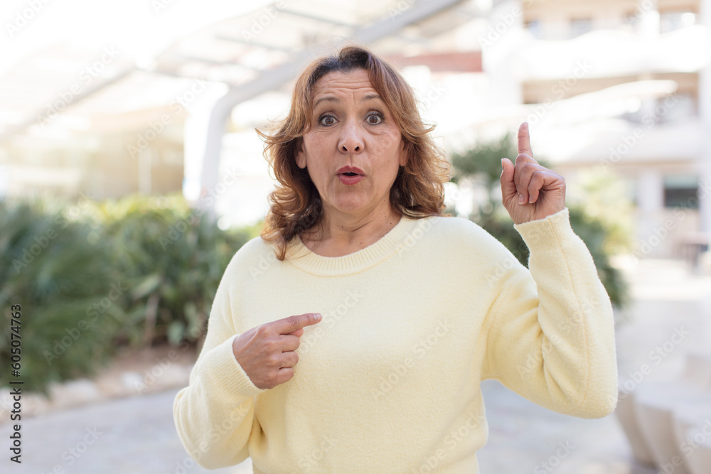 middle age woman feeling proud and surprised, pointing to self confidently, feeling like successful number one