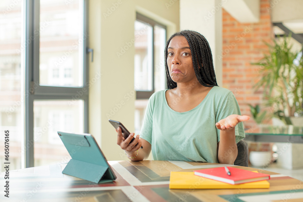 Fototapeta premium black afro woman shrugging, feeling confused and uncertain. studying concept