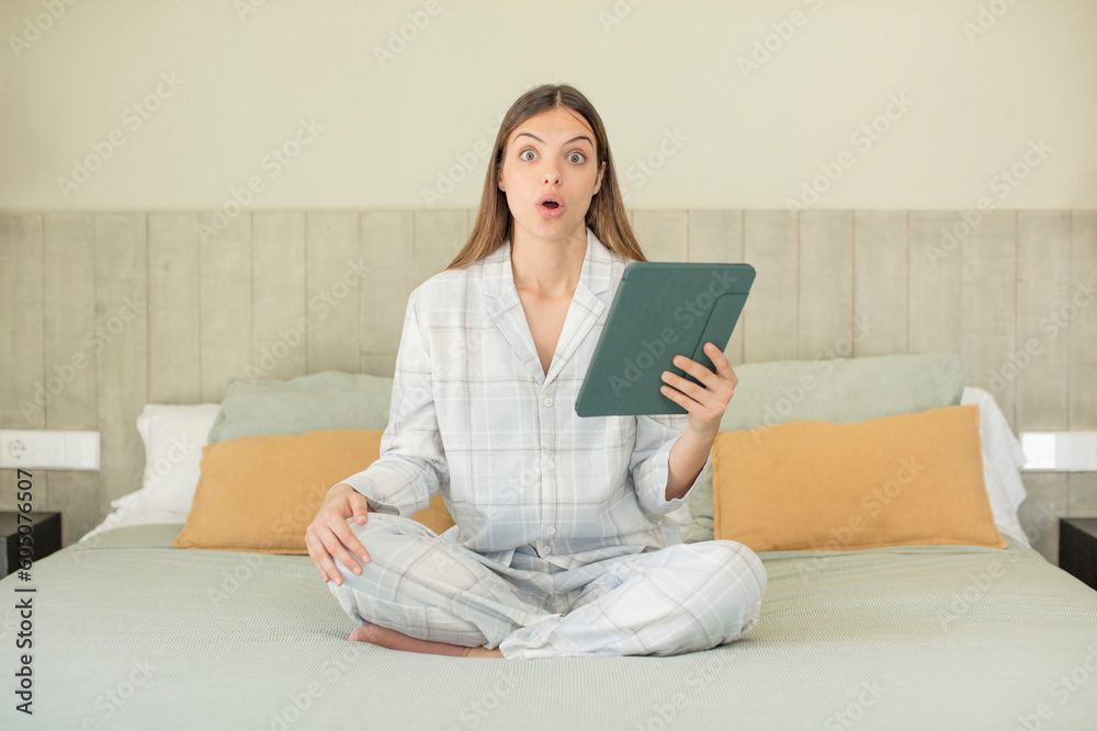 young pretty woman feeling extremely shocked and surprised. touchscreen pad concept young pretty woman feeling extremely shocked and surprised. touchscreen pad concept