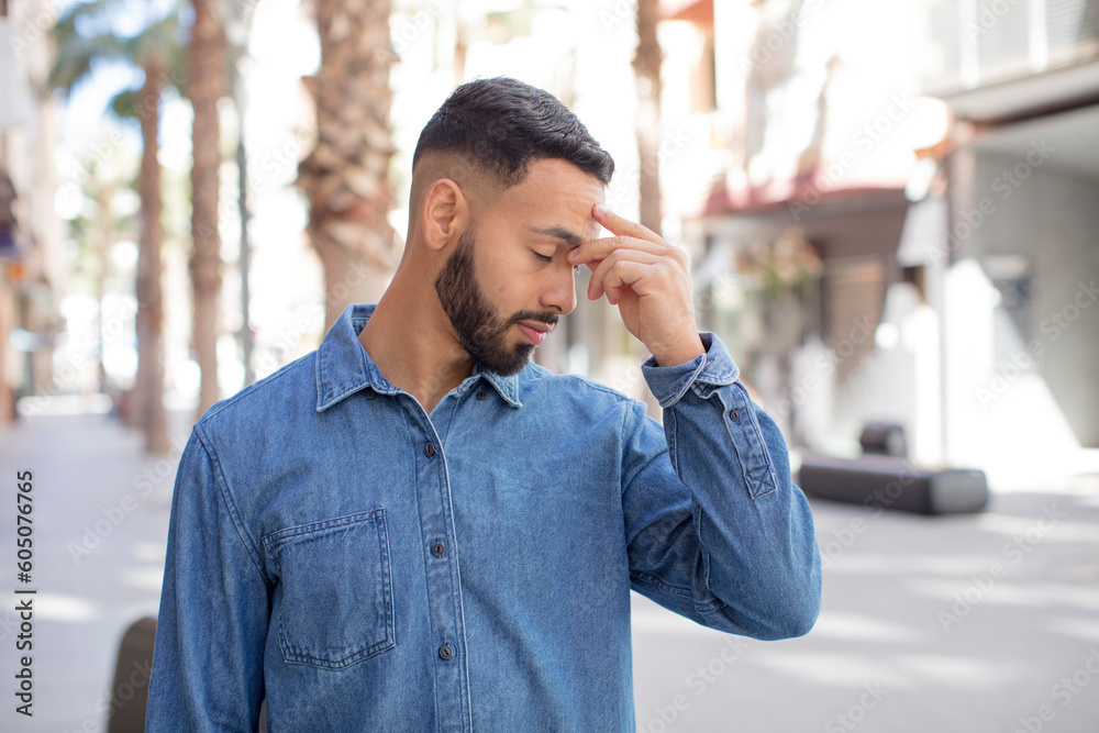 young handsome man feeling stressed, unhappy and frustrated, touching forehead and suffering migraine of severe headache young handsome man feeling stressed, unhappy and frustrated, touching forehead and suffering migraine of severe headache