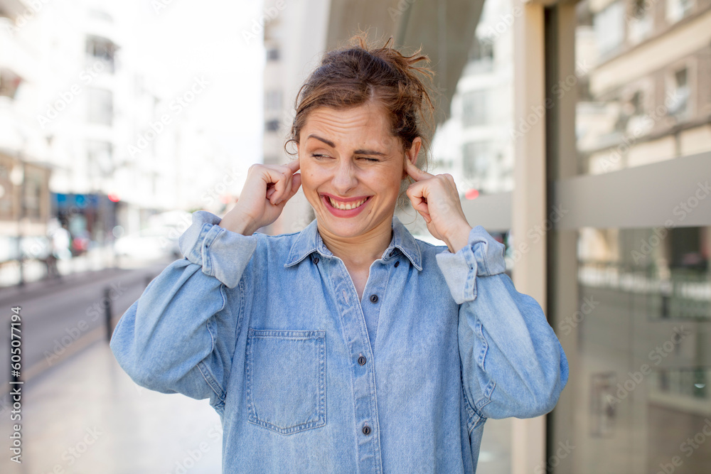 pretty young woman looking angry, stressed and annoyed, covering both ears to a deafening noise, sound or loud music pretty young woman looking angry, stressed and annoyed, covering both ears to a deafening noise, sound or loud music