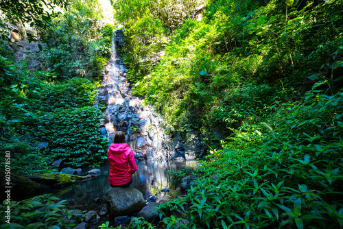 Girl in a pink jacket sits and admires unique, beautiful waterfall on Canungra Creek Circuit trail, Lamington National Park (O'Reilly's), Gold Coast, Queensland, Australia photo