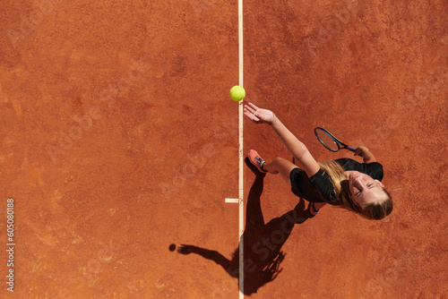 Top view of a professional female tennis player serves the tennis ball on the court with precision and power