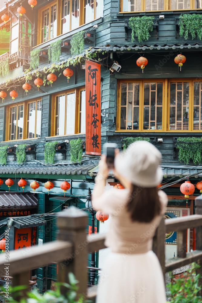 Naklejka premium woman traveler visiting in Taiwan, Tourist taking photo and sightseeing in Jiufen Old Street village with Tea House background. landmark and popular attractions near Taipei city. Travel concept