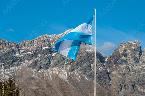 Light blue and white Argentinian flag waving with a mountain and blue sky as a background in patagonia argentina