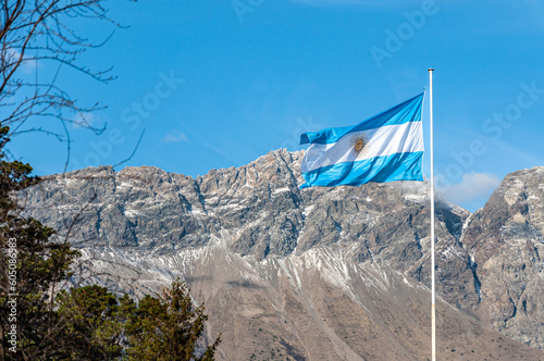 Light blue and white Argentinian flag waving with a mountain and blue sky as a background in patagonia argentina