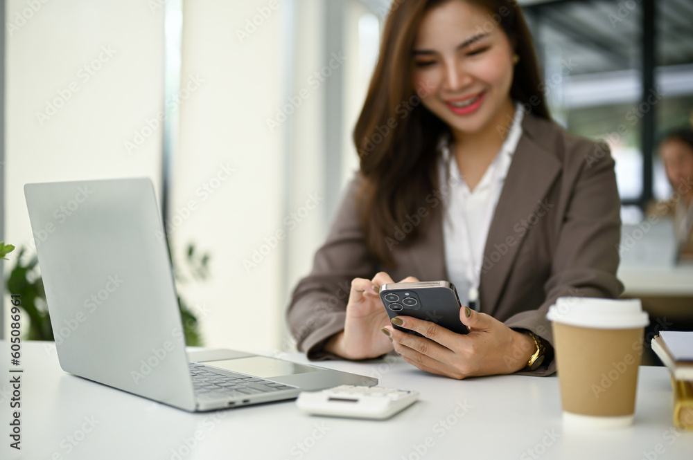 A businesswoman using her smartphone at her desk. A businesswoman using her smartphone at her desk.