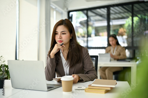Wallpaper Mural Focused Asian businesswoman looking at her laptop screen, pensive thinking a plan Torontodigital.ca