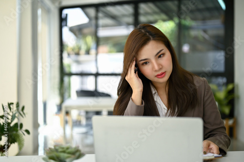 Free Download Stressed Asian businesswoman looking at her laptop screen with serious face - GFXLoad