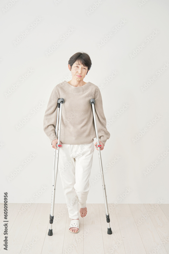 部屋で松葉杖を使いながら困る中年女性 カメラ目線 部屋で松葉杖を使いながら困る中年女性 カメラ目線