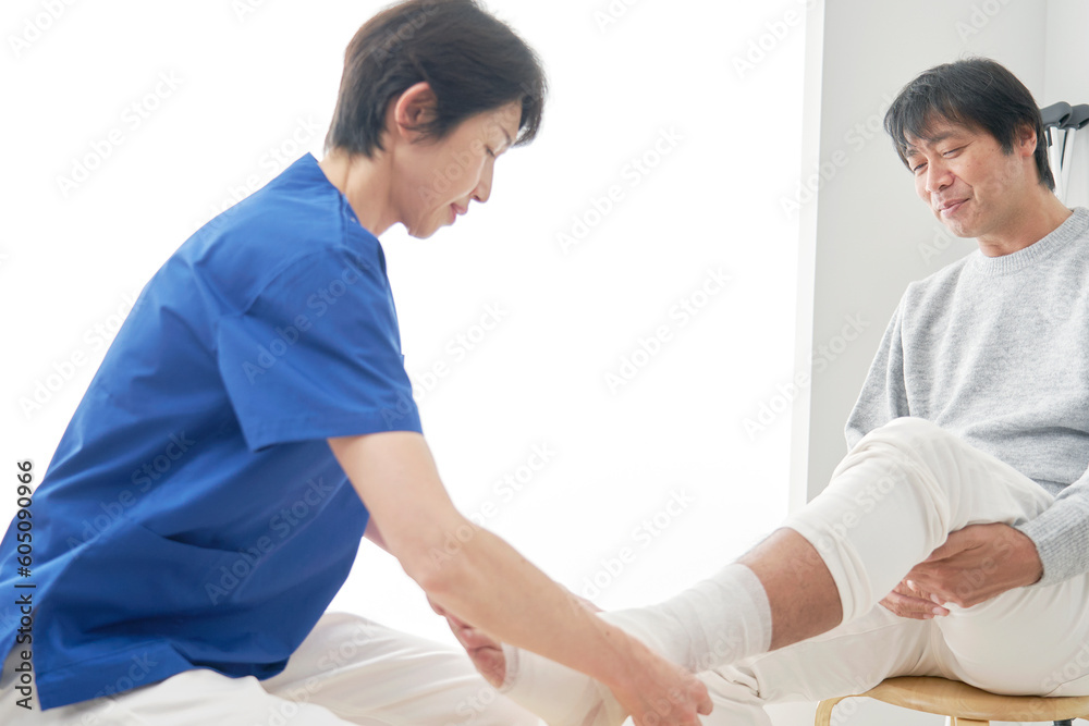 Obraz premium 足首に包帯を巻く看護師