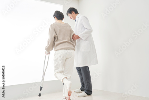 医者と松葉杖を使って歩く中年女性 © siro46