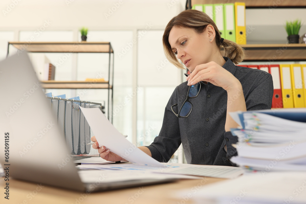 Woman worker holds glasses reading investigation document Woman worker holds glasses reading investigation document