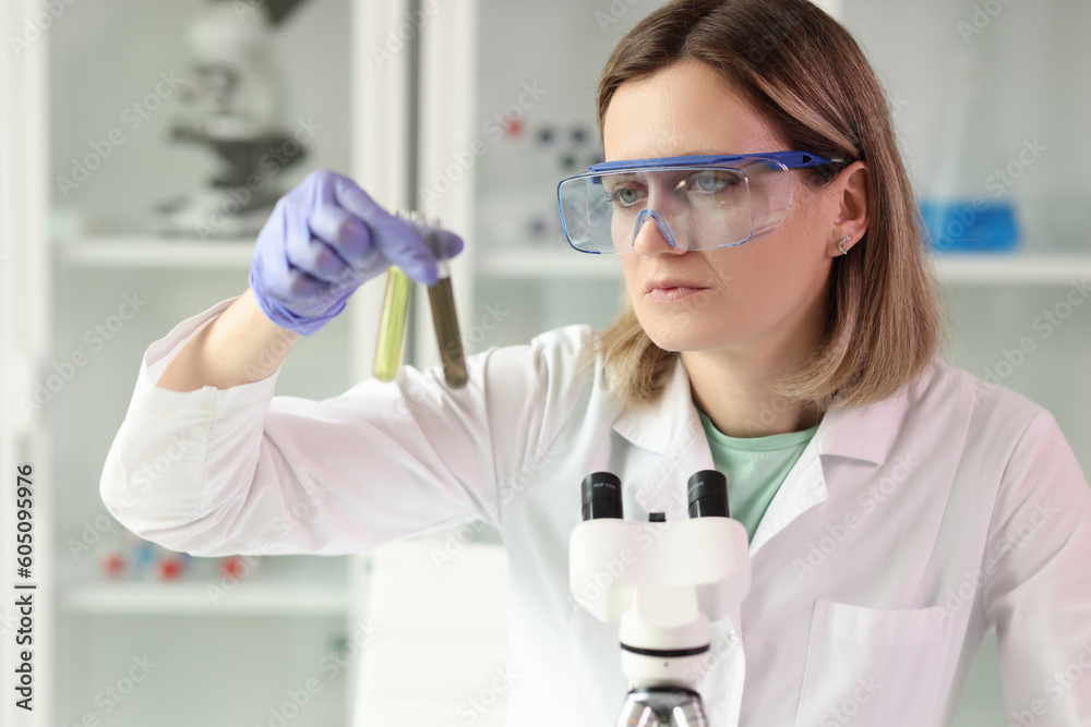 Fototapeta premium Woman holds test tubes with yellow and brown liquids samples