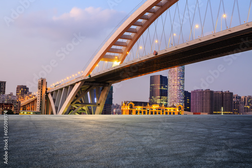 Asphalt road and bridge with urban architecture at sunset