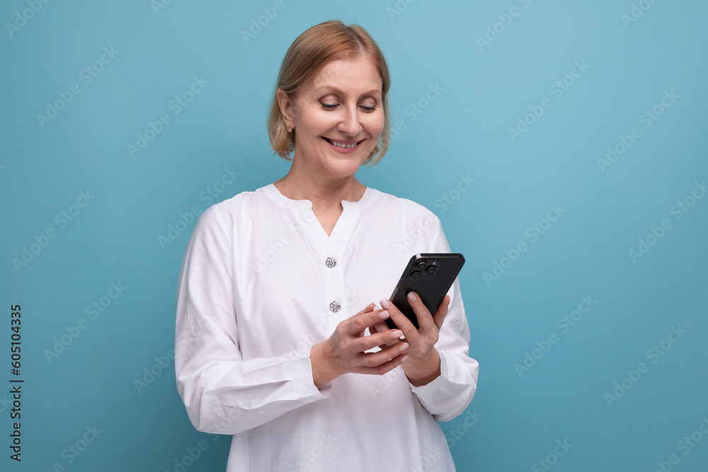 healthy slim blond mature woman mastering technique using smartphone on studio background healthy slim blond mature woman mastering technique using smartphone on studio background