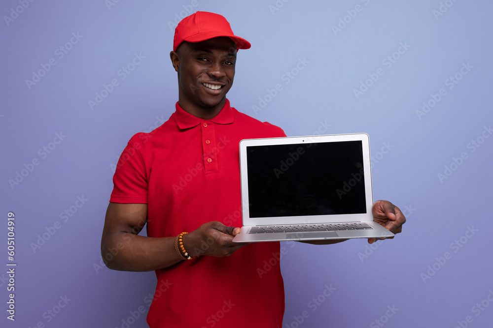 american service employee man in red cap and t-shirt holding laptop with mockup american service employee man in red cap and t-shirt holding laptop with mockup