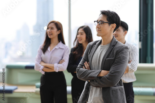 Collaborative process of young asian business people team working together discussing, researching, brainstorming and planning while crossed arms in business office building and city background