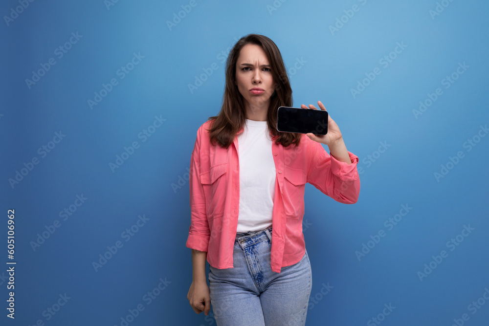 surprised young woman in pink shirt and jeans with phone on studio isolated background surprised young woman in pink shirt and jeans with phone on studio isolated background