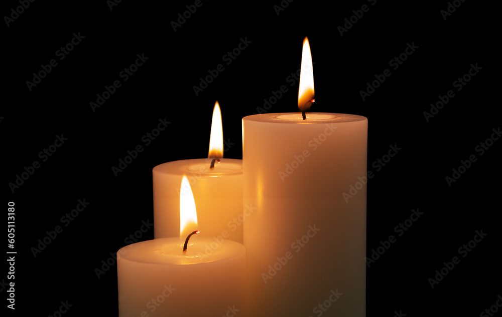Three white burning candles isolated on black background. Three white burning candles isolated on black background.