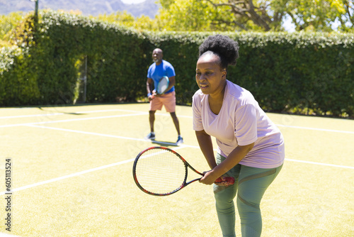 Happy senior african american couple playing doubles on sunny grass tennis court © wavebreak3