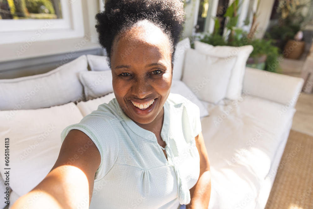Portrait of happy senior african american woman smiling during video call in sunny living room