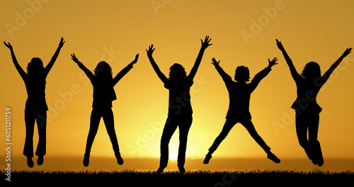 Happy friends jumping at sunset background