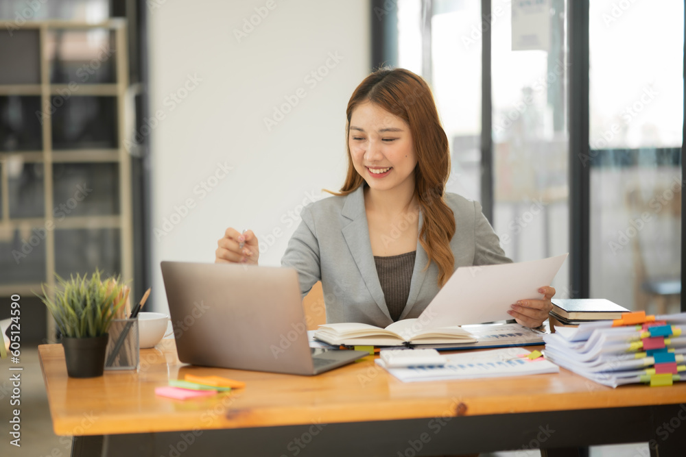 Asian businesswoman holding notebook about business, spending money Asian businesswoman holding notebook about business, spending money