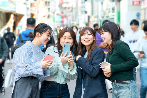 Foto 街中でスマホを使う若い女性達