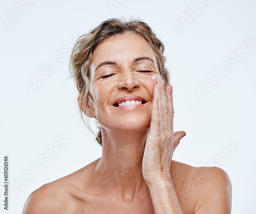 Skincare, smile and a woman with an anti aging cream isolated on a white background in a studio. Happy, moisturize and a mature model with facial lotion for beauty, wellness and care of skin