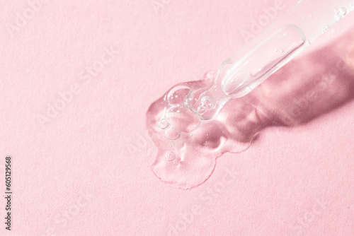 Pipette dropper and liquid smear with bubbles on pink background. Serum, collagen, enzyme, peptides,hyaluronic acid swatch, © vasanty