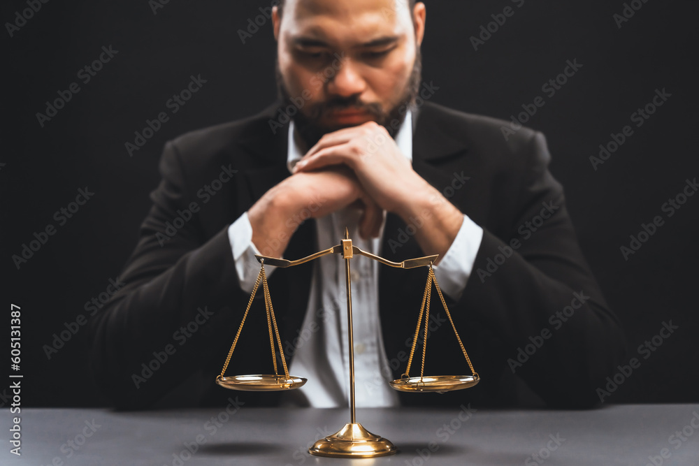 Focus golden scale balance with burred background of lawyer in black suit sit on his office desk, symbol of legal justice and integrity, balanced and ethical decision in court of law equility - obrazy, fototapety, plakaty 