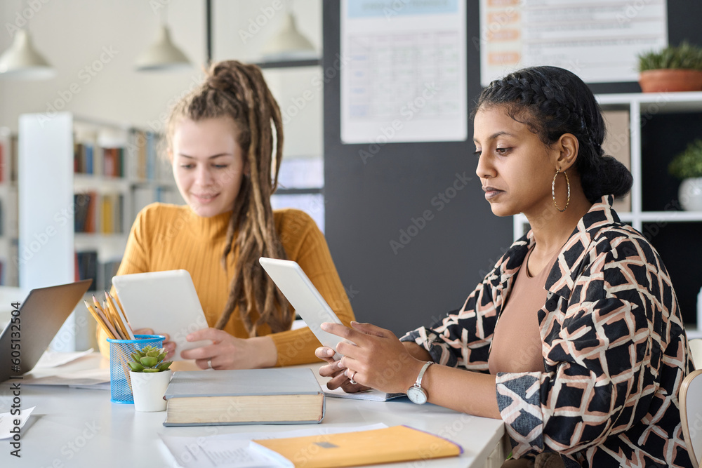 Students watching online lesson on digital tablet while sitting at desk and studying in class Students watching online lesson on digital tablet while sitting at desk and studying in class