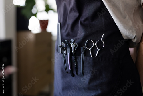 Midsection of caucasian male hairdresser wearing black apron with hairdressing tool in front pocket photo