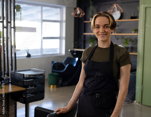 Portrait of caucasian female hairdresser with short bob and highlights smiling at hair salon