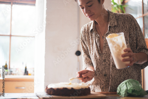 Asian person icing birthday cake at home by window in germany