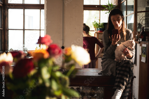 woman looks at phone device at home with dog on lap and roses photo