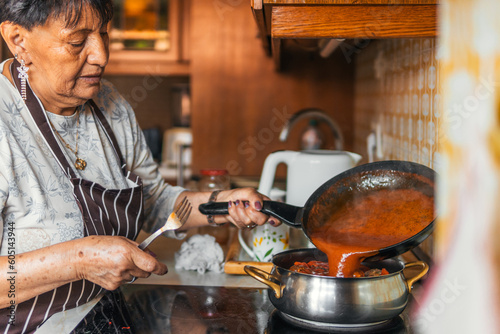 older latin american woman immigrant mixing sauce cooking meatloaf