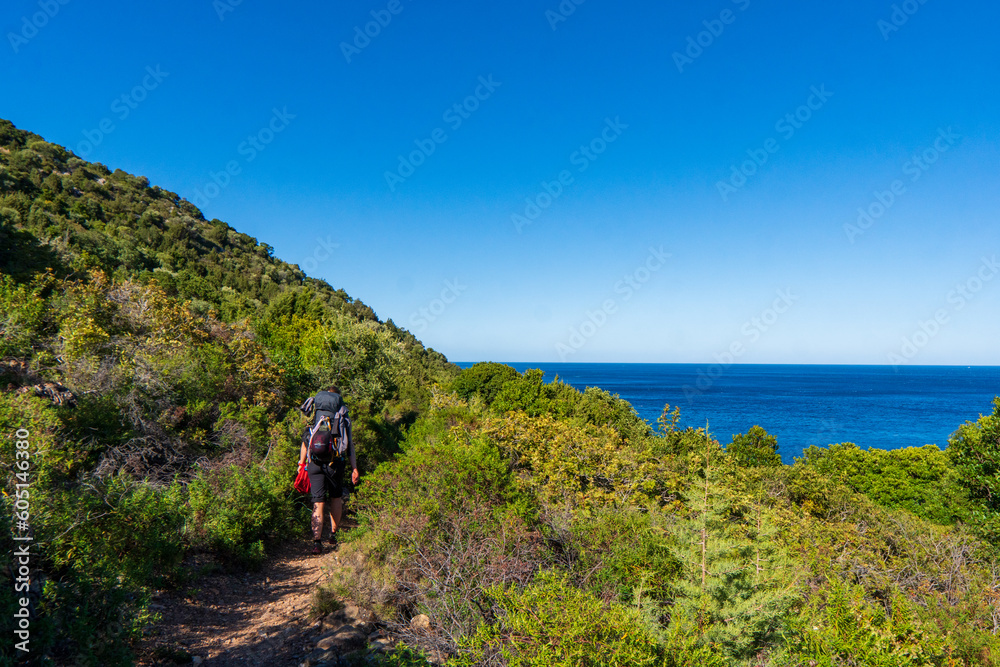 young woman tourist with backpack on background panoramic view from the mountains on the island of Sardinia in clear weather, Monte Corrasi, Italy