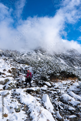 Hiker woman standing and looks around, admiring winter mountain landscape. Happy tourist woman in winter. High Tatras, 1987 meter above sea level. Slovakia