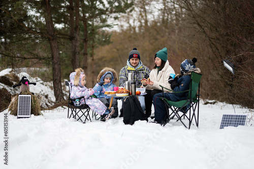 Family with three children in winter forest spending time together on a picnic.