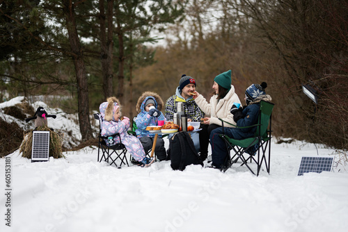 Family with three children in winter forest spending time together on a picnic.