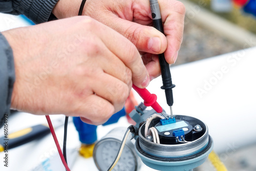 Checking gas equipment sensor with multimeter. Close-up hands. Diagnostics of industrial equipment.