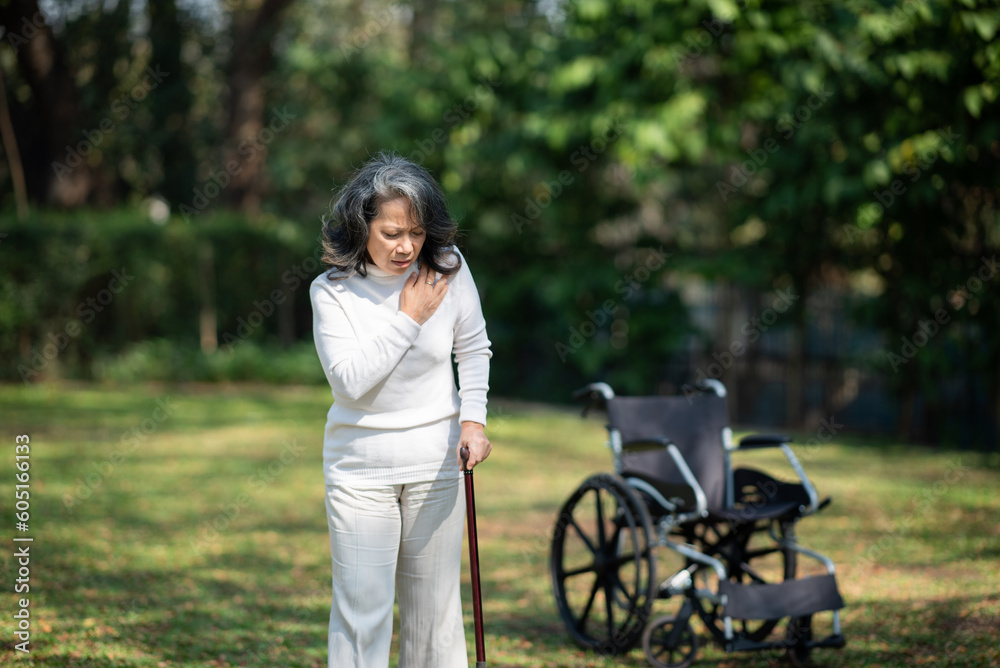 Asian old woman sitting on a wheelchair outdoors in the garden There is pain in the heart Asian old woman sitting on a wheelchair outdoors in the garden There is pain in the heart