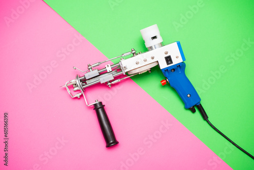 A tufting gun against a bright pinkang green colored background.	