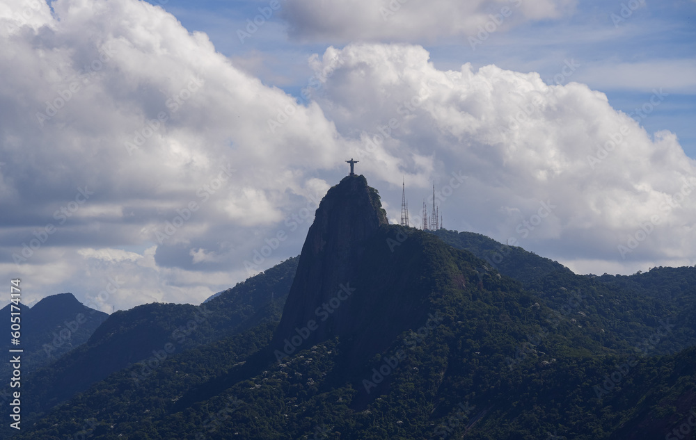 Landscape of Rio de Janeiro with Jesus statue landmark on top of the hills during a sunny day with blue sky and white clouds.