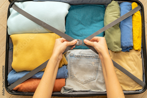 Top down view of female hands packing suitcase for summer vacation. The concept of travel, flights on an airplane, vacation at sea.